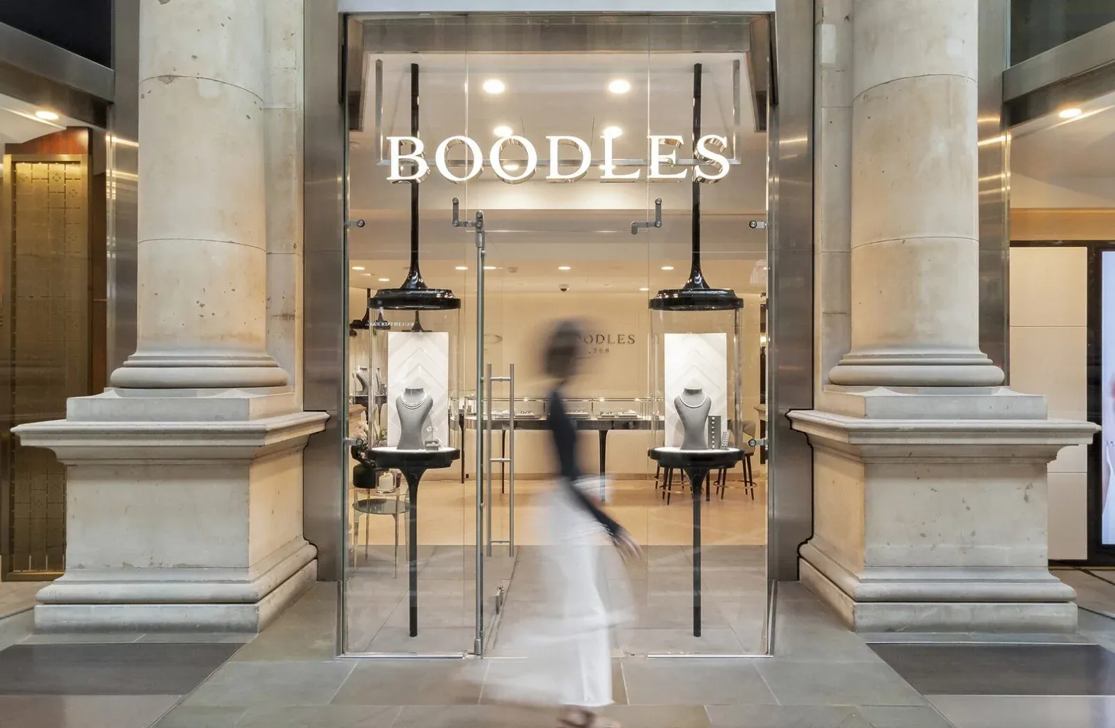 Boodles jewellery shopfront with necklaces on display as a shopper walks past