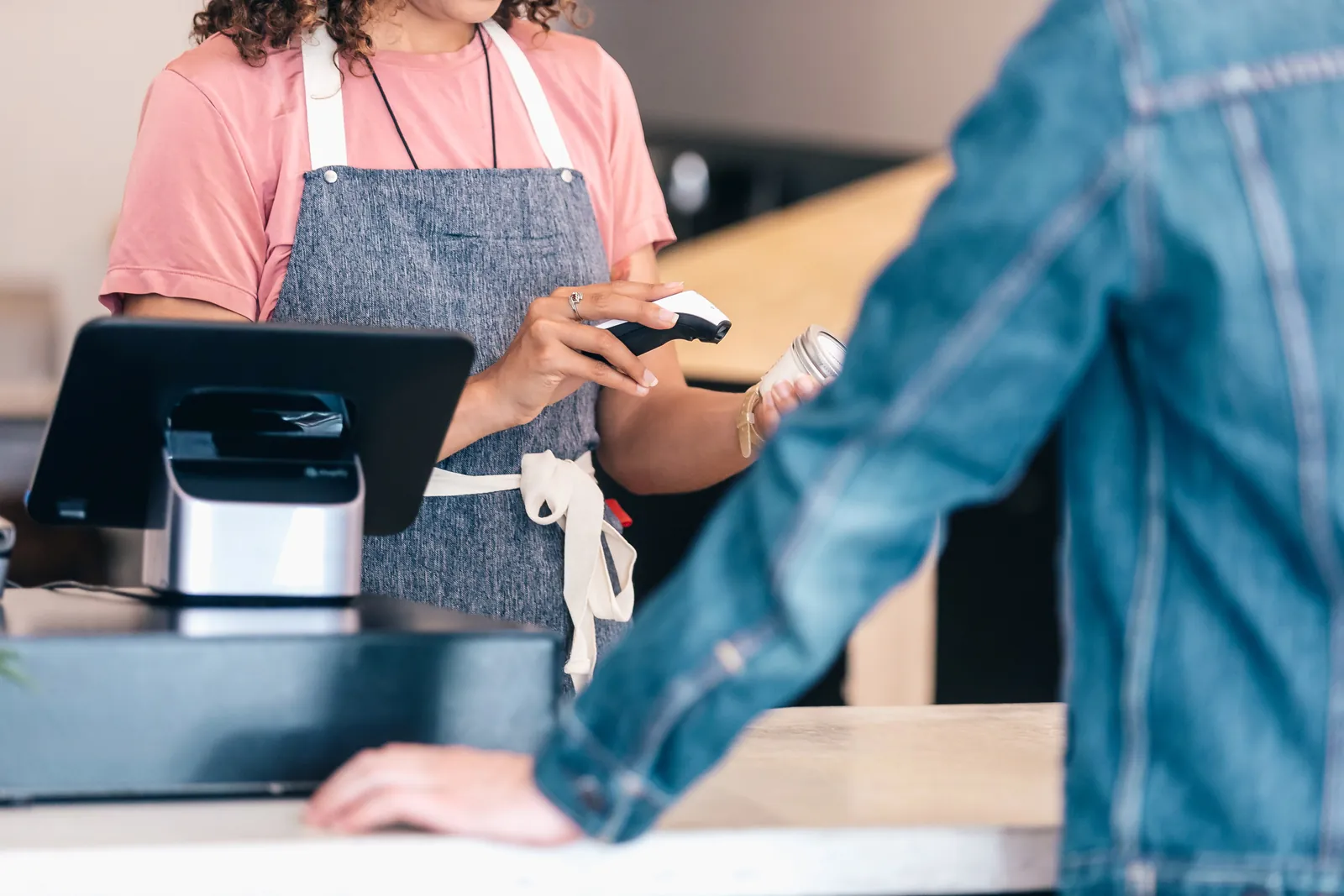 Shop assistant scanning a product at the till for a customer